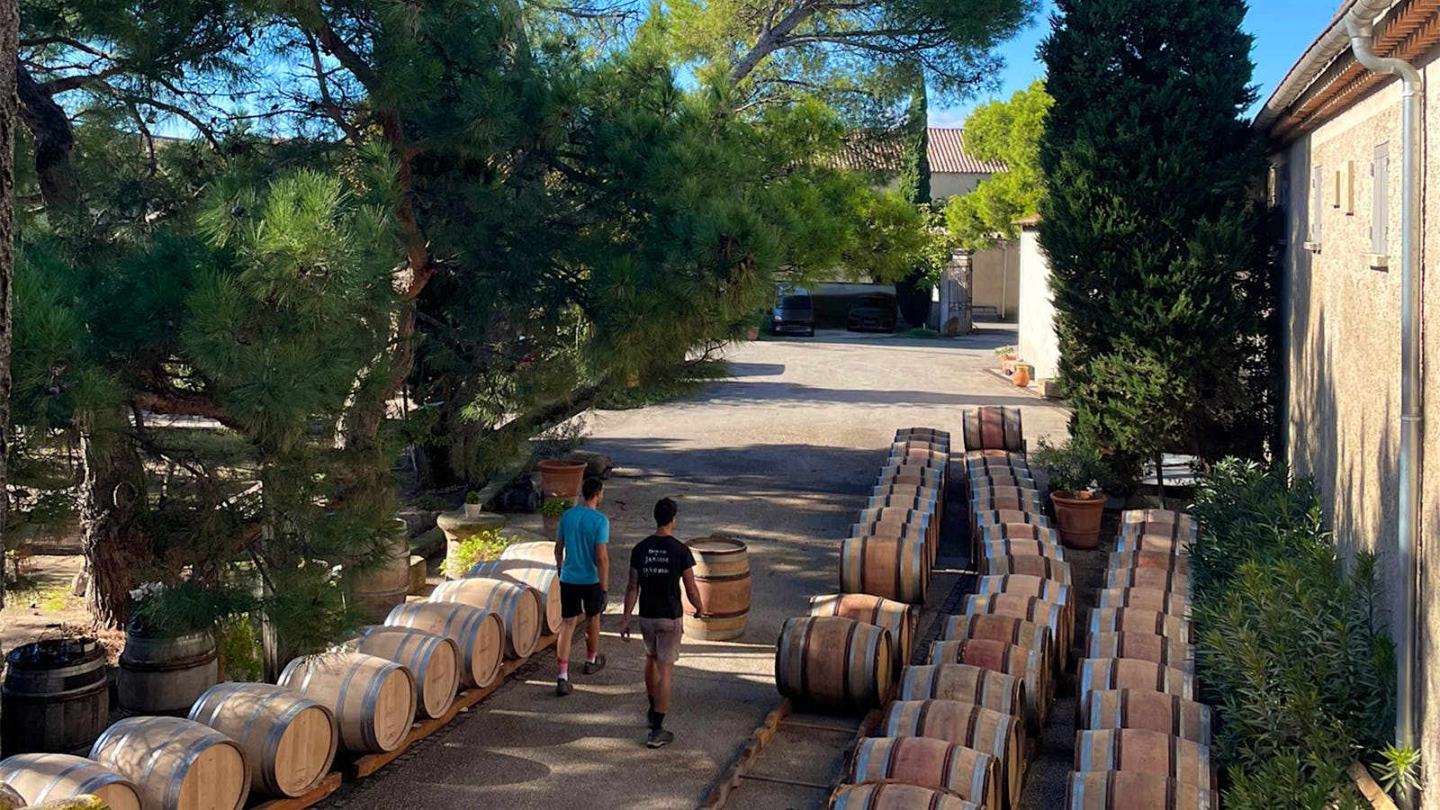  Two winery workers walk past barrels outside Domaine de la Janasse's winery