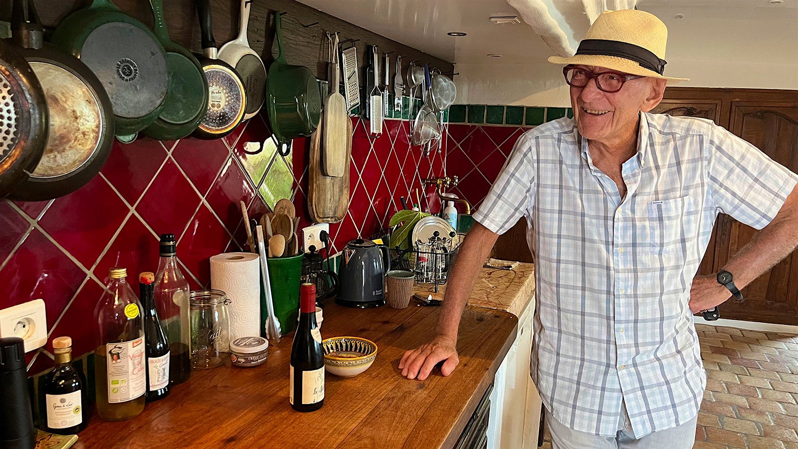 Kermit Lynch in his kitchen in Provence, with pots and pans hanging from the wall