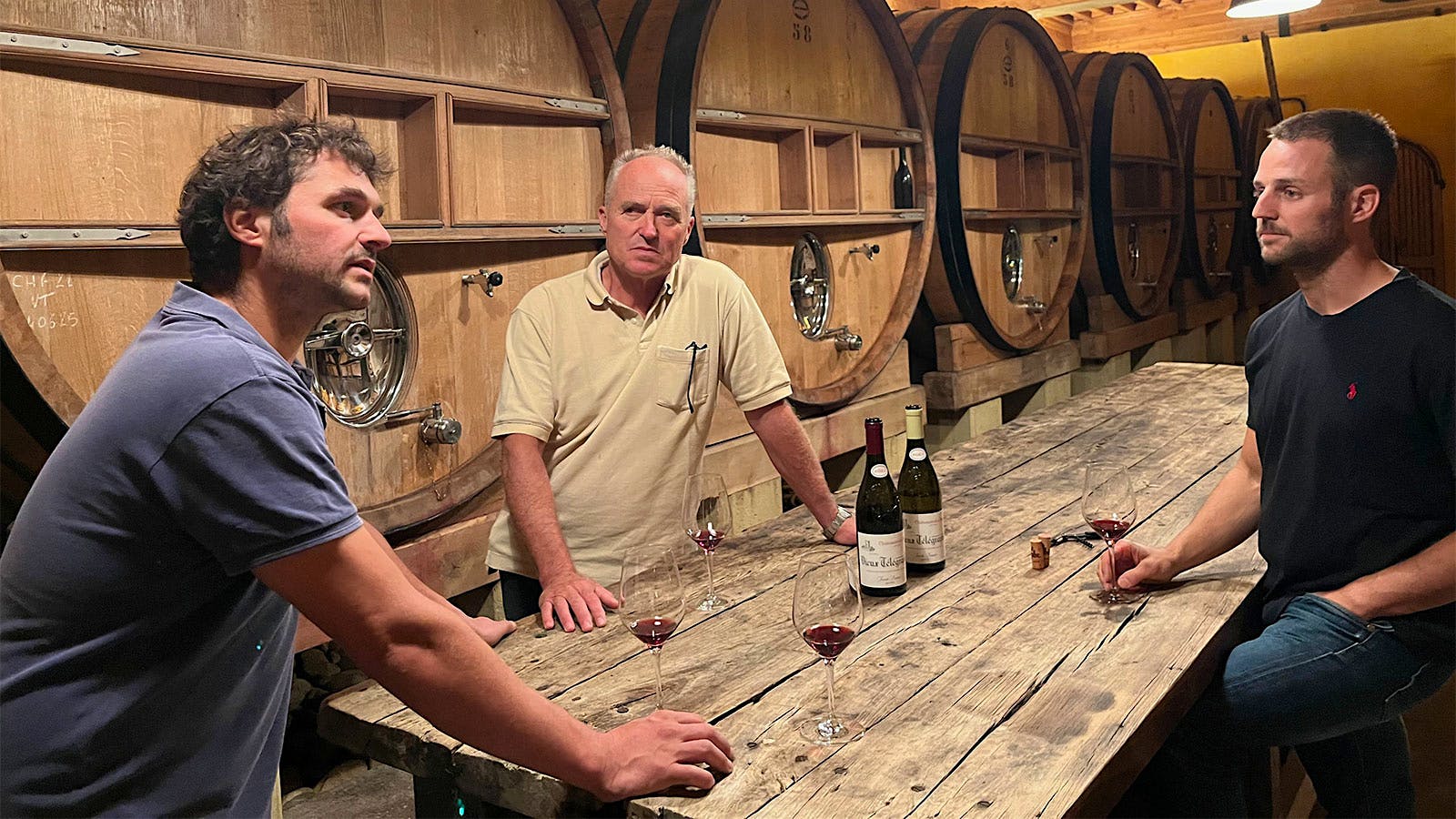  Edouard, Daniel and Nicolas Brunier tasting Vieux T&eacute;l&eacute;graphe wines together in front of large oak casks