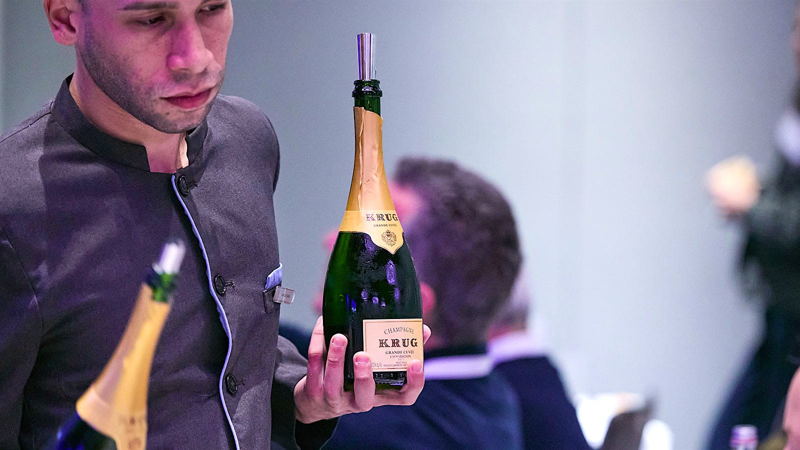 A wine steward holding two bottles of Krug Champagne at New York Wine Experience