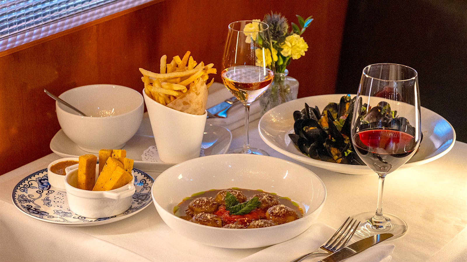  Glasses of wine and several dishes from Nice Matin, including mussels, meatballs and fries