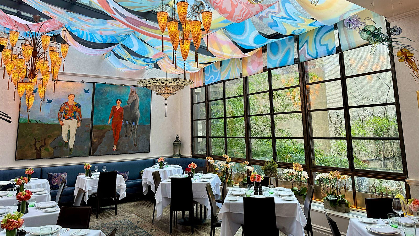 The dining room of Sistina in New York City, with large paintings, bunting and chandeliers