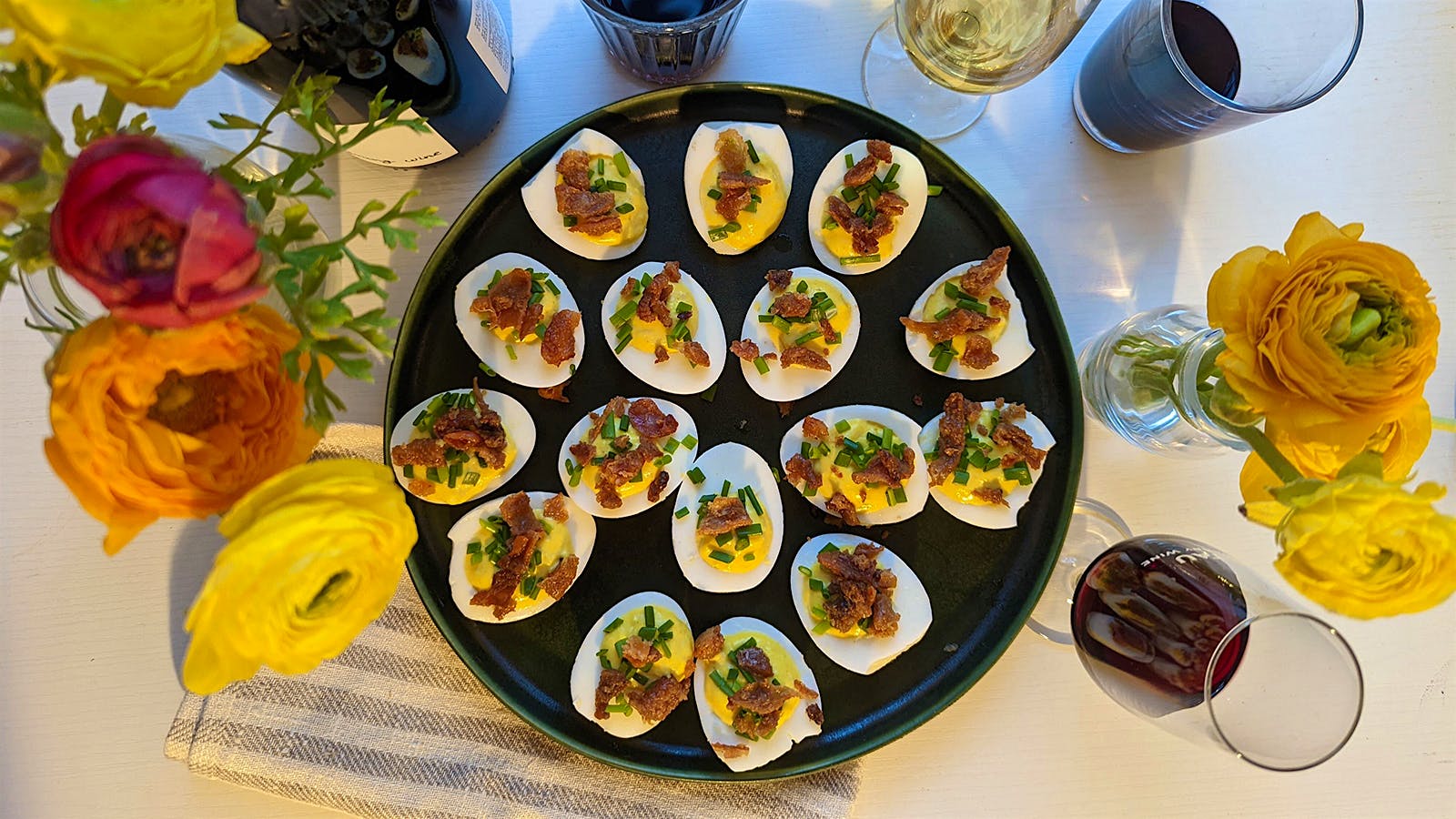  Horseradish deviled eggs with chives and gribenes, with glasses of wine.