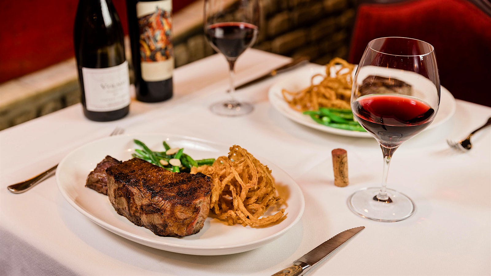  A table at Bern&rsquo;s Steak House with wines and plates of steaks.