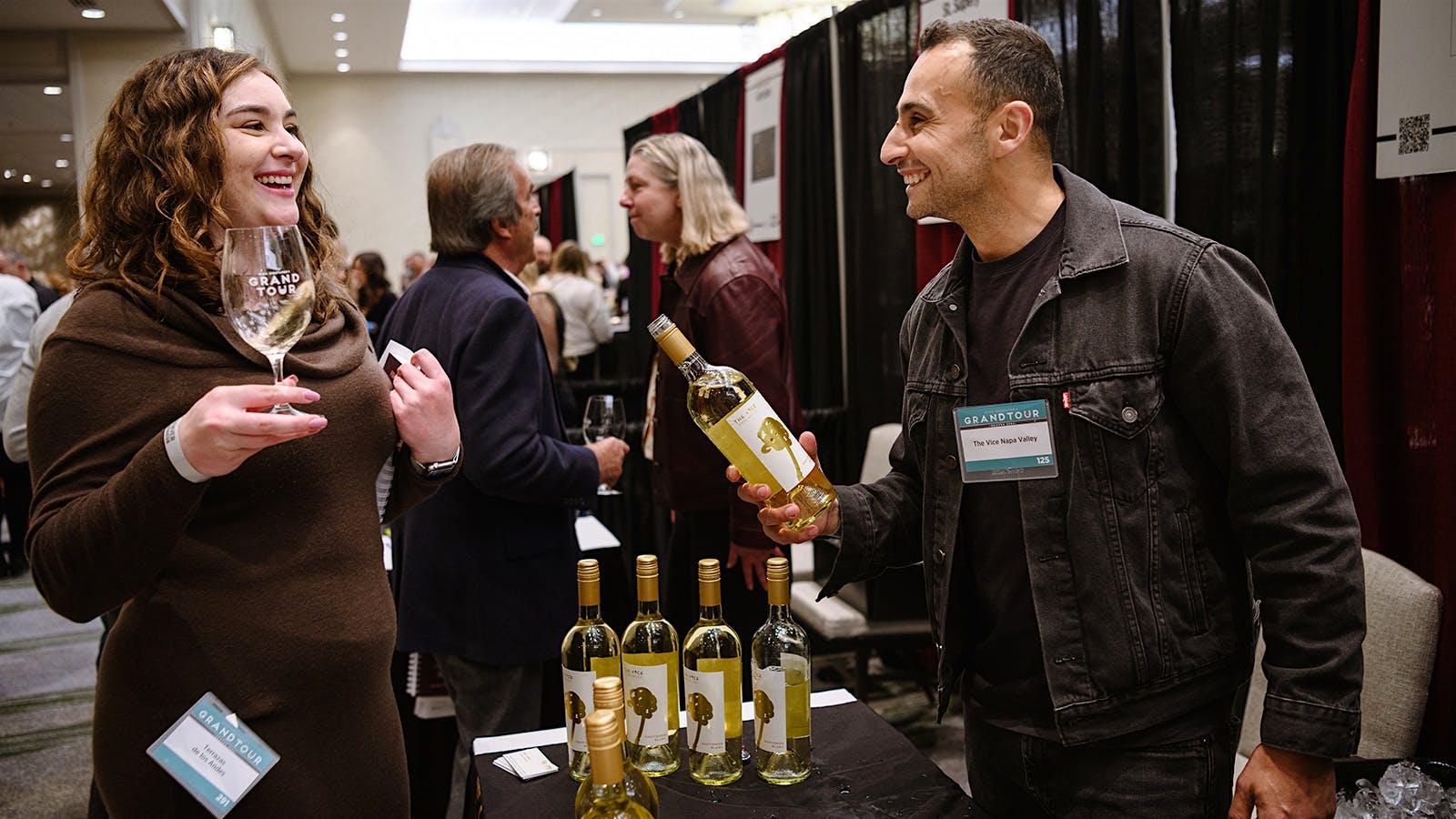Presenter Malek Amrani interacts with a guest while pouring a glass of Sauvignon Blanc at the 2026 Wine Spectator Grand Tour in Denver, Colorado.