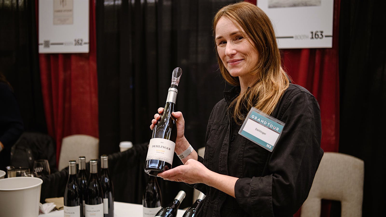Winery representative Carmen Dehlinger from Dehlinger Wines at the 2026 Wine Spectator Grand Tour in Denver Colorado, presenting a bottle of Dehlinger Pinot Noir Russian River Valley Altamont 2022.