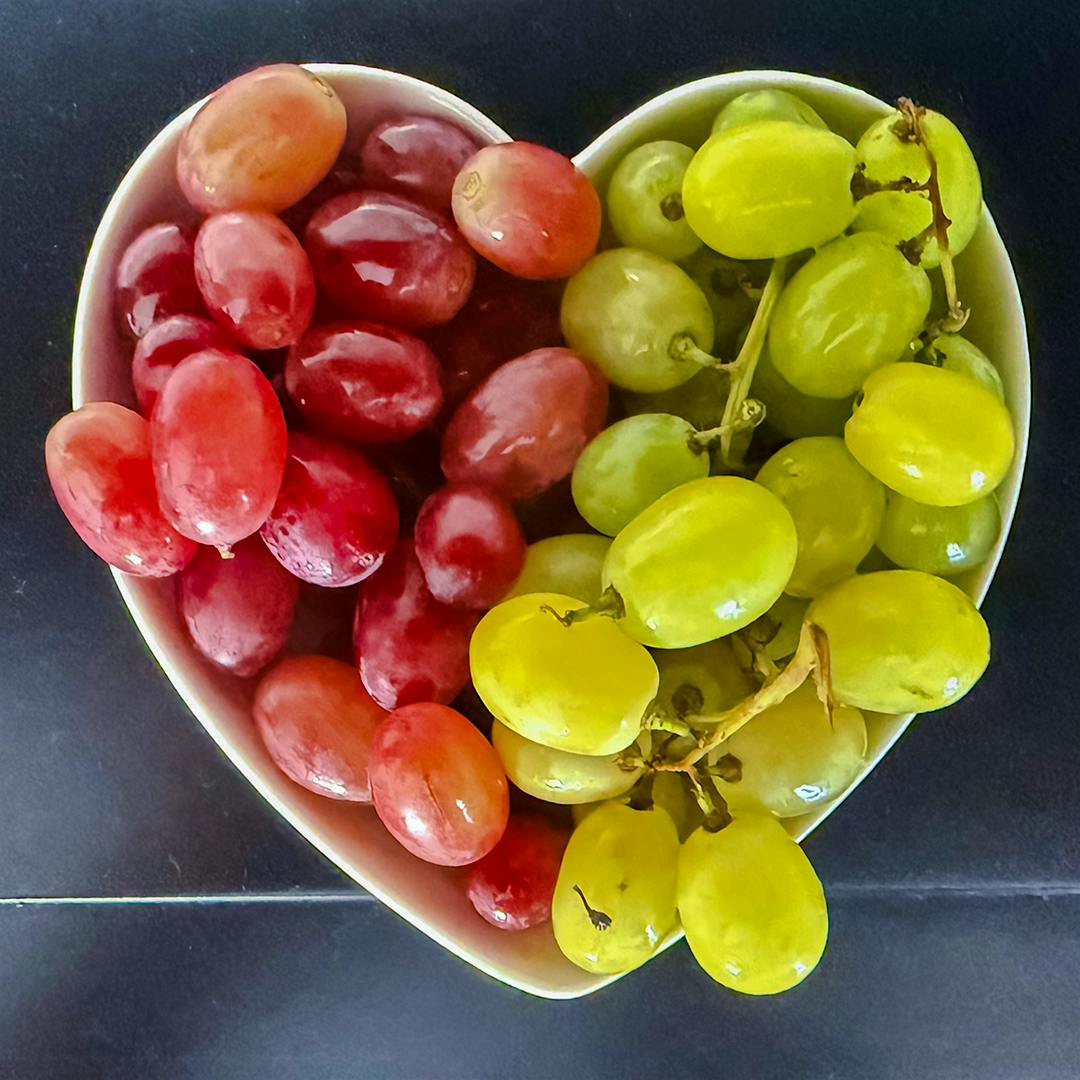 A heart-shaped bowl of grapes.