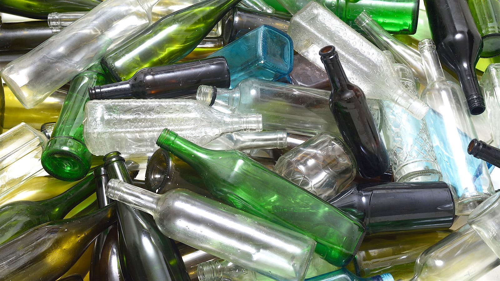 Closs-up of unmarked, multi-colored wine bottles in a recycling bin.