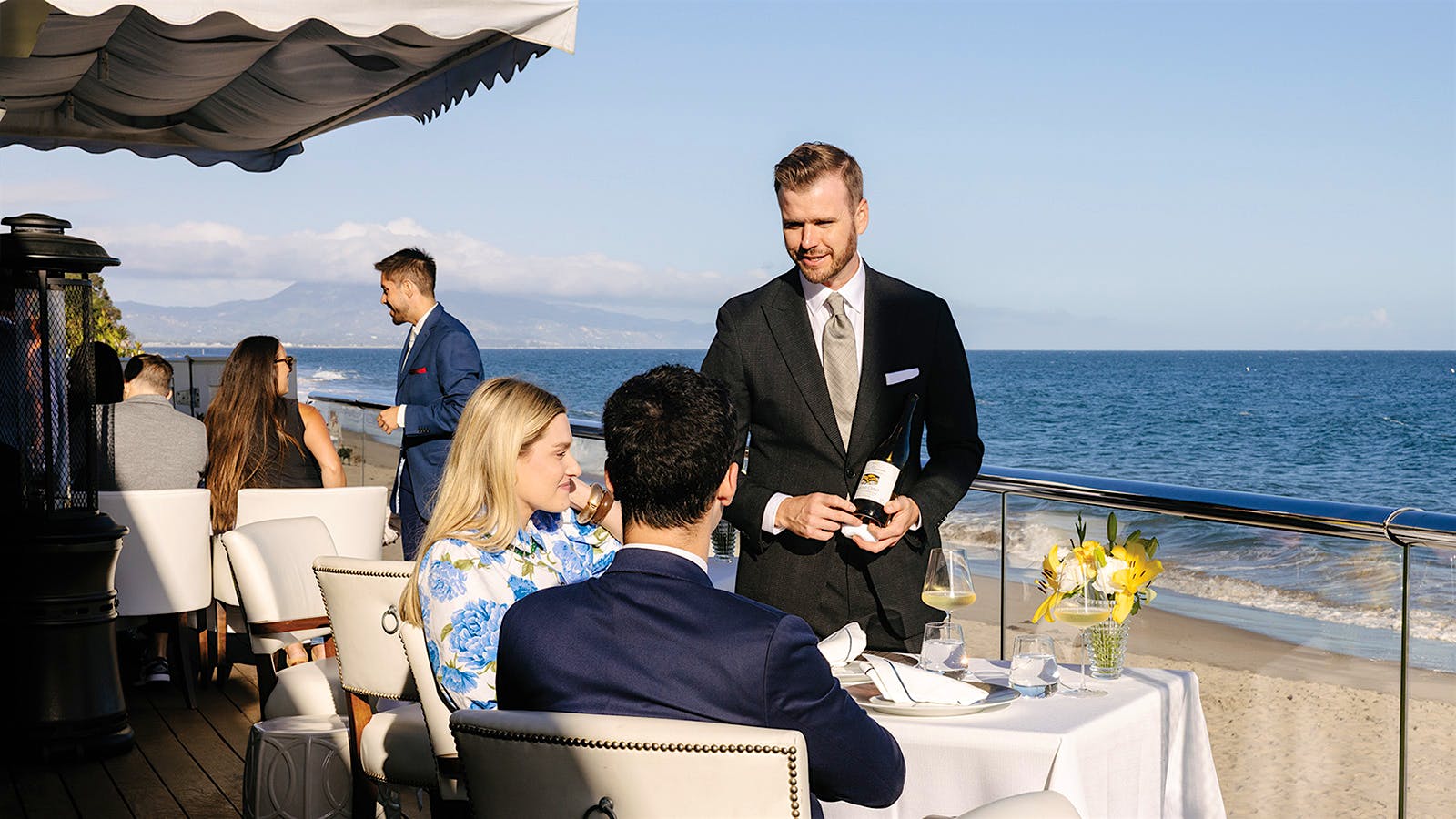  Guests dining on the shore at Caruso's, being served by wine director Rob Smit.