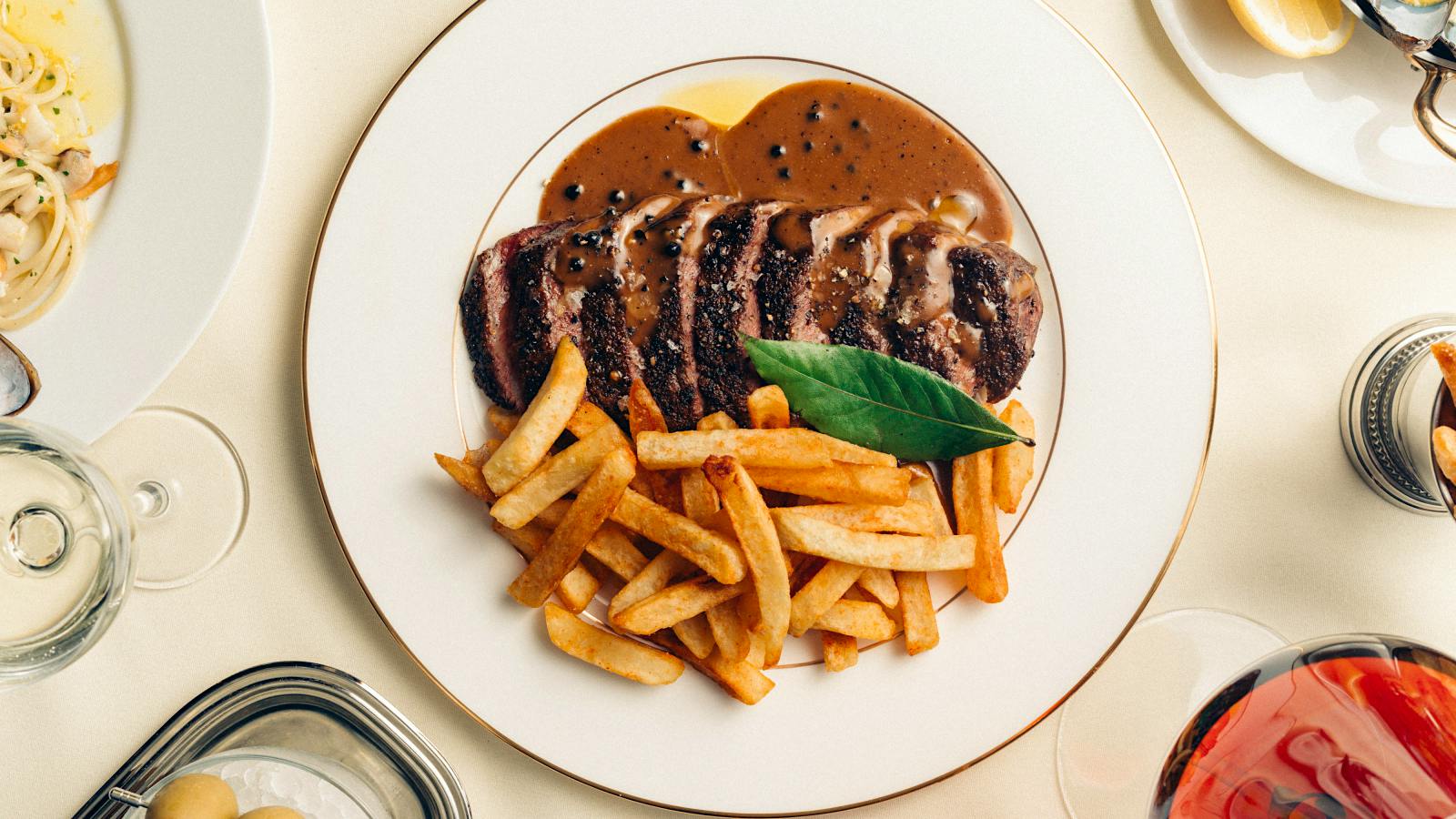 Cafe Charmant’s menu is heavy on seafood, but there are plenty of brasserie classics, including steak frites in peppercorn sauce.Catch Hospitality Group Tries a French Accent With Cafe Charmant