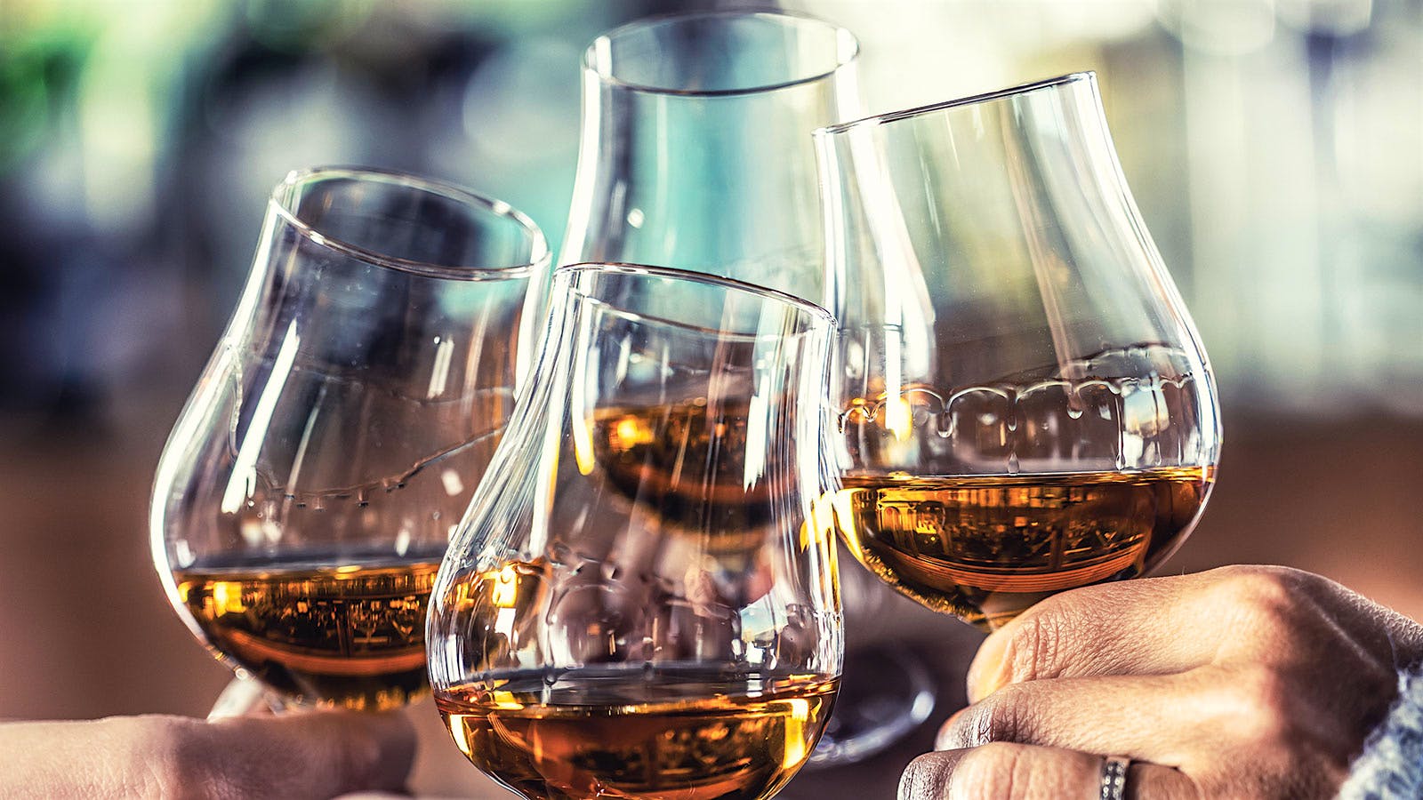 A close-up of four people toasting with Glencairn glasses full of whisky