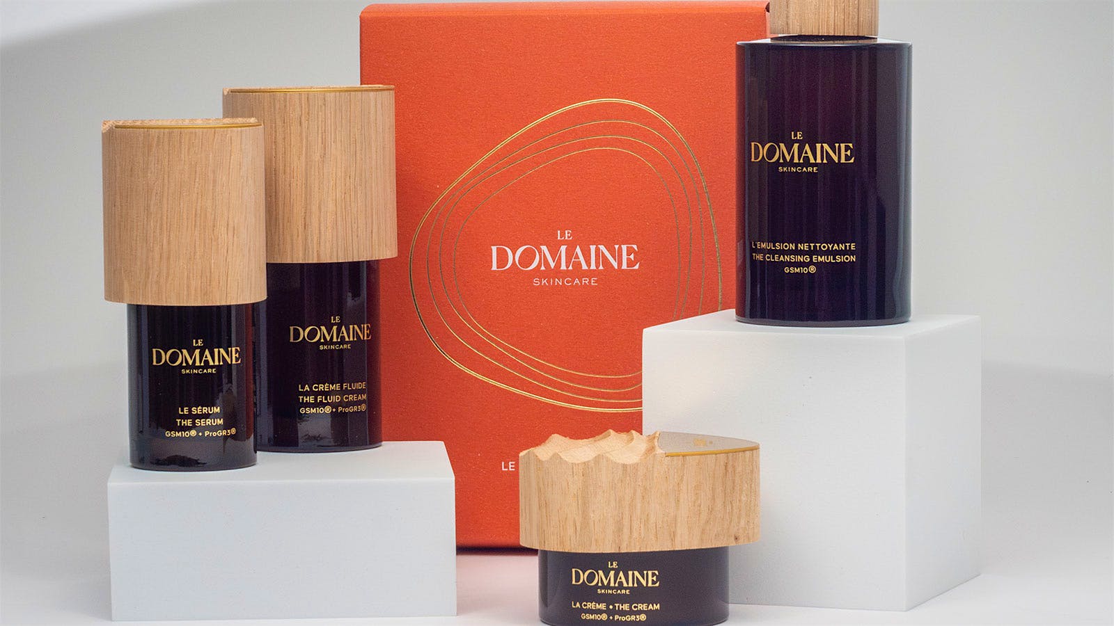  Multiple Le Domaine skincare products are displayed in jars at verying levels.