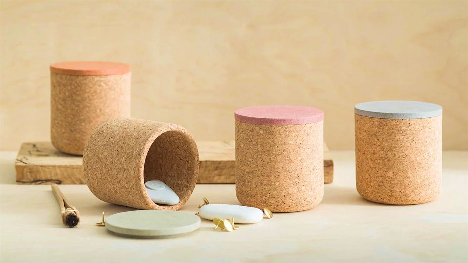  Four cannisters made from cork with colorful lids sit side by side, with one knocked over.] 