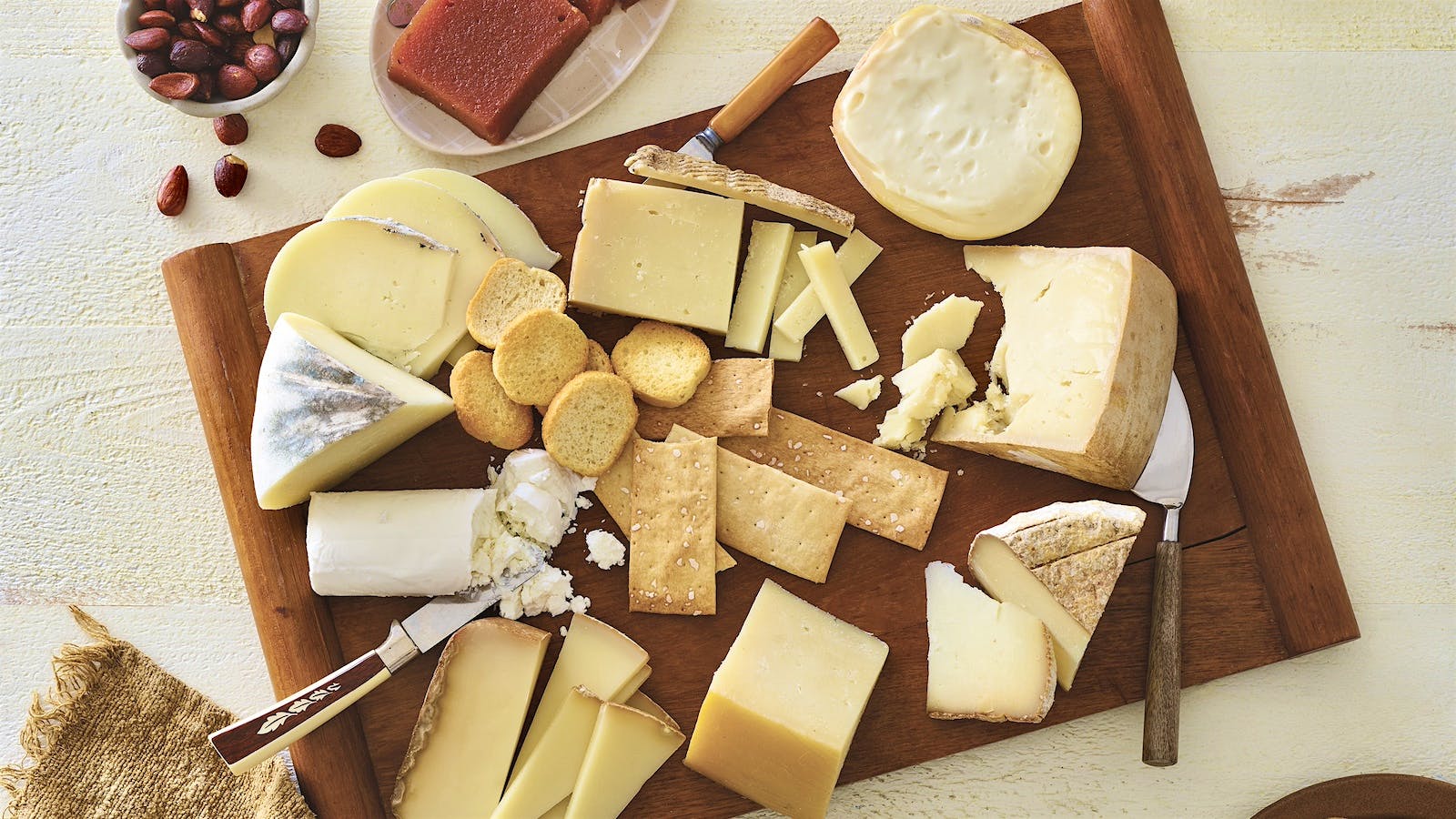 A cheese plate with eight sheep’s milk cheeses of various styles interspersed with crackers, crostini, and cheese knives