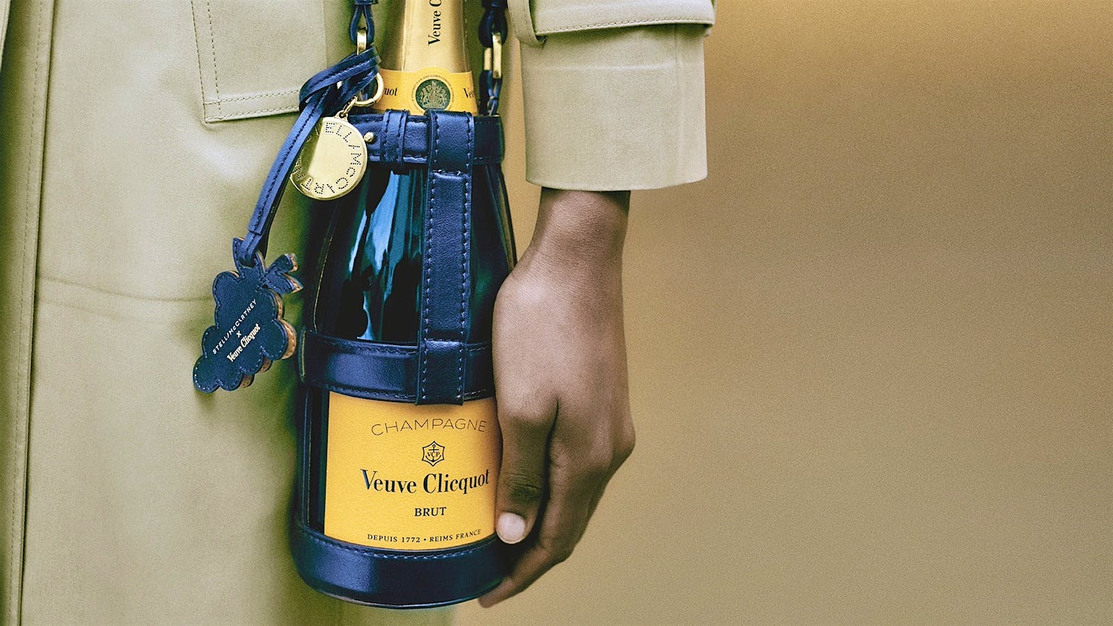 A model holds a bottle of Veuve Clicquot Champagne in a vegan leather bottle holder designed by Stella McCartney