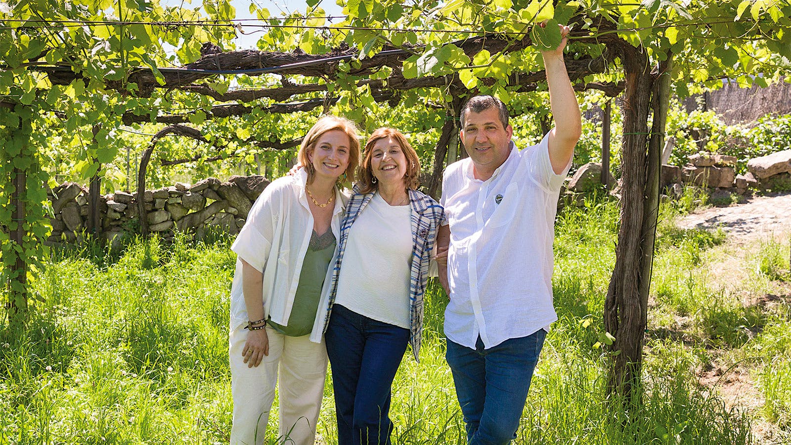 From left to right: Maria João, Maria Palmira Cedeira, and António Luís stand together in a Soalheiro vineyard in Vinho Verde, Portugal.