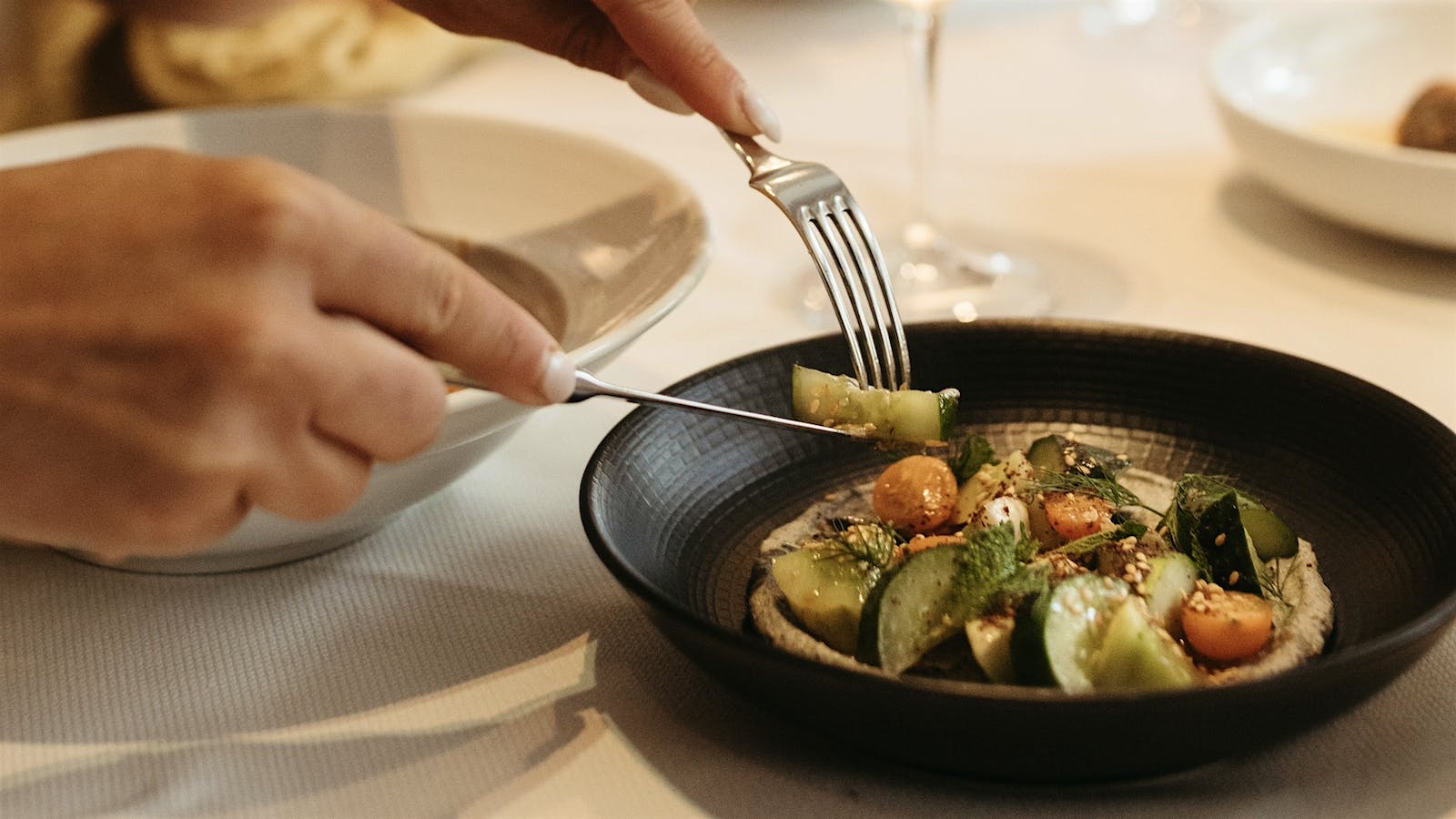 A diner serves themselves from a plate of Italian cucumber salad with sun-dried tomatoes and sesame at Ai Fiori in New York