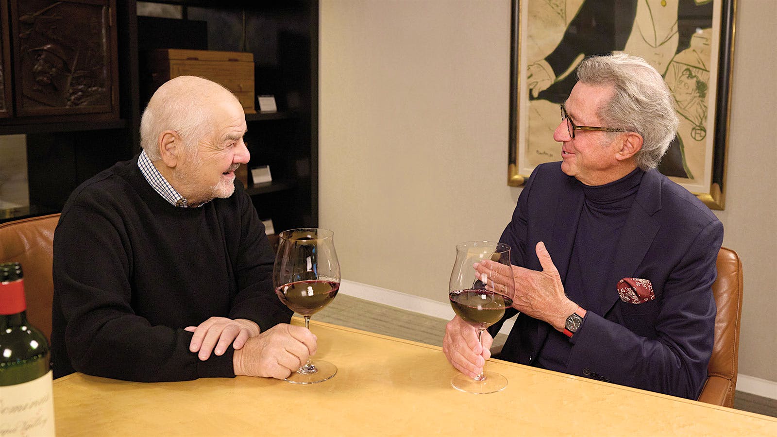 Wine Spectator editor and publisher Marvin R. Shanken and Christian Moueix sit together with glasses of red wine.