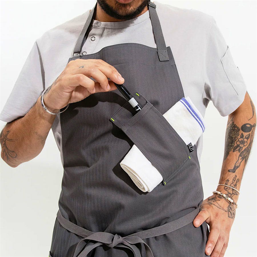 Designed for functionality in the kitchen, the Tilit Utility Apron features spots for towels, pens and more.