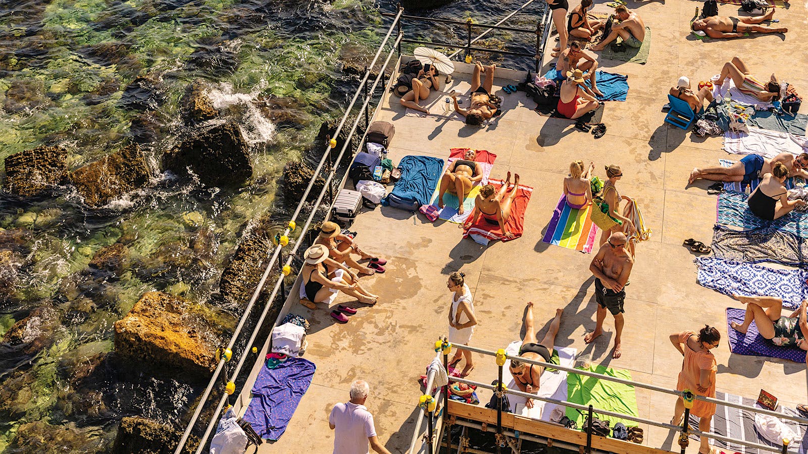 Sunbathers gather on a terrace overlooking the Mediterranean Sea in Siracusa, Sicily.