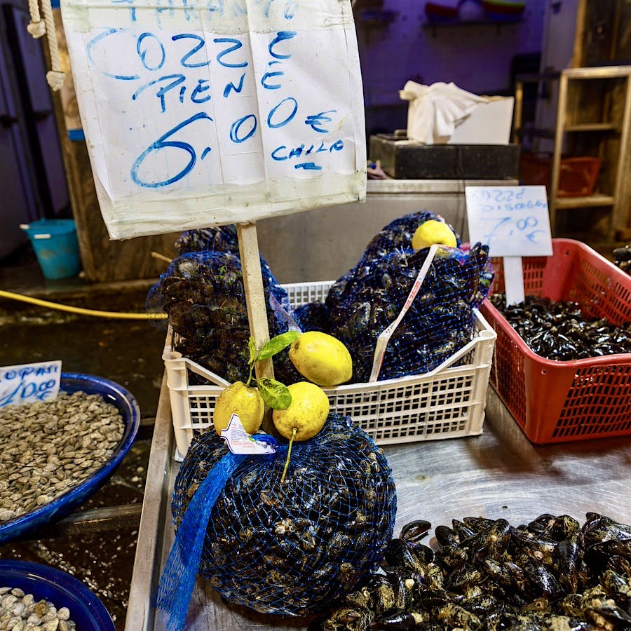 Fresh-caught mussels sold with lemons at a fish market in Campania, Italy.